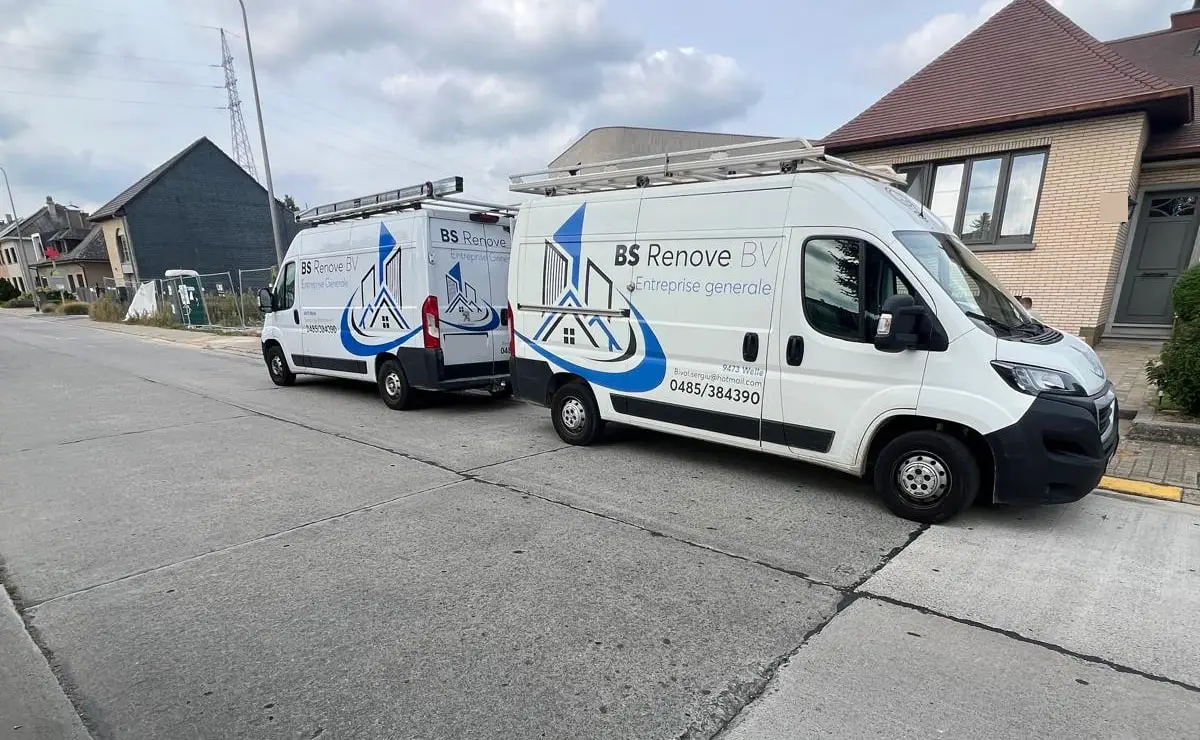 Deux camionnettes blanches BS Renove, avec le logo bleu, garées dans une rue
